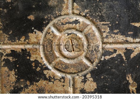 Bottom of an old worn black metal container with a screw head in the center