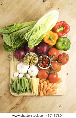 Vegetables on a wooden kitchen table, lit with a large light source from the right.
