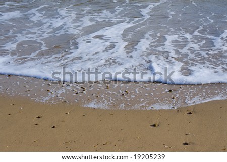 A foamy wave retreating from a beach