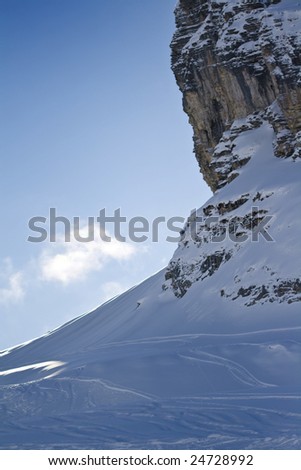 a view of a cliff face with some ski tracks below
