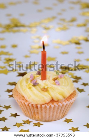 A single birthday cupcake with candle and star decorations