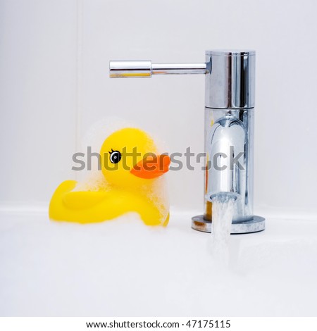 Rubber duck waiting to be played with at bath time covered in bubbles