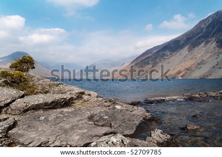 Rocks reaching out into a lake with mountains in the distance