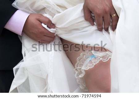 stock photo Groom lift a wedding dress to show a traditional garter