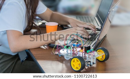 Students code a metal car robot and an electronic board. Robotics and electronics. Laboratory. Mathematics, engineering, science, technology, computer code. STEM education.