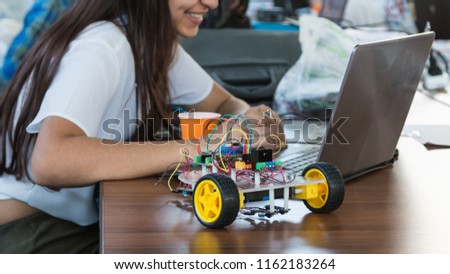 Students code a metal car robot and an electronic board. Robotics and electronics. Laboratory. Mathematics, engineering, science, technology, computer code. STEM education.