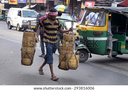 Labor carry daily house hold product in basket at the busy street of Calcutta on July 07, 2015 in Calcutta, India.