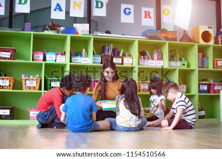 woman teacher in classroom teaching preschool kids, joyful learning together with mixed-race international children