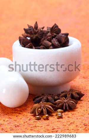 Star Anise in white granite mortar and pestle on textured background