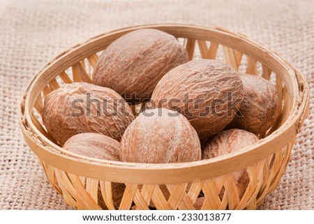 Nutmeg in basket on jute background