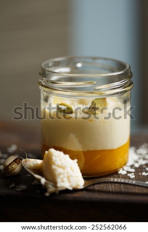 Panna cotta with mango, coconut and pistachios on a wooden cutting board