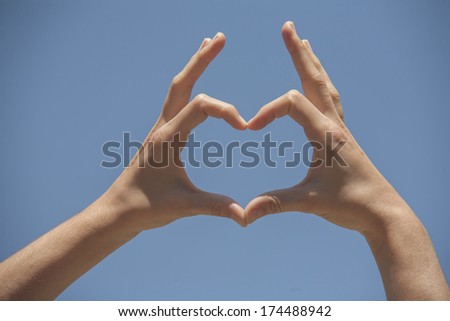 Hands in the shape of heart on the blue sky