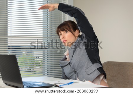 The image of business woman doing exercise at the office