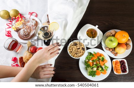 Table with healthy and unhealthy food and alcohol. Woman hands covering the part with harmful dishes and drinks with table cloth. Dieting after Christmas and New Year celebration.