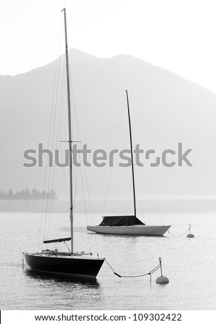 Two sail boats in early morning on the mountain lake. Black and white photography. Salzkammergut, Austria.