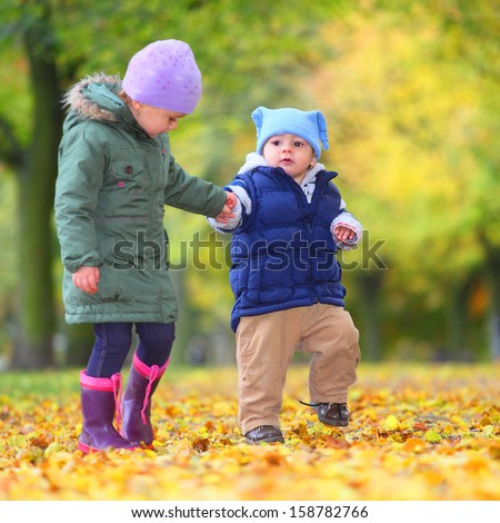 Funny kids playing in yellow foliage.  Autumn in the city park.