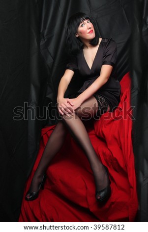 stock photo Beautiful brunette woman in black nylons posing on a red 