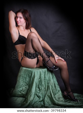 Low key lighting studio shot young attractive women in black sexy lingerie on green brocade background