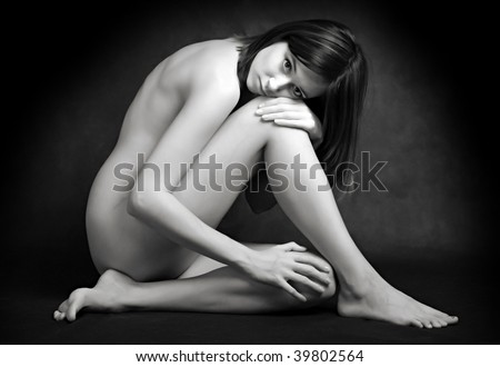 Classical artistic nudity style picture of woman sitting on black background