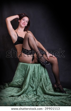 Low key lighting studio shot young attractive women in black sexy lingerie on green brocade background