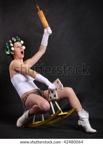 Screaming militant feminist with rolling pin ridden on a wooden hobby horse. Humorous image. Great for calendar.