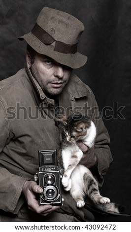 Poor photographer with antique camera (TLR) and spotted cat. Humorous image. Low key studio shot. Great for calendar. Trademark Flexaret is 50 years old - today don\'t exist. Czech made camera.