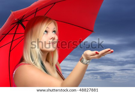 A pretty young girl holding an umbrella checks to see if it is raining, against cloudy sky.
