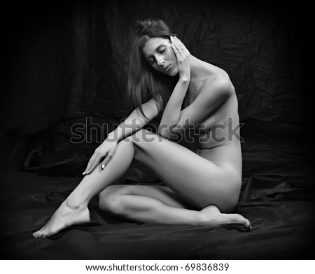 Monochrome photography of sad woman sitting on black background.