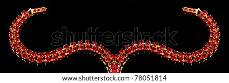 Golden necklace with red jewels on a black background and space for your text.
