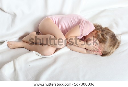 Worried crying child lying on a bed.