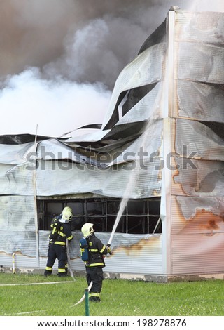 PILSEN, CZECH REPUBLIC - JUNE 12 2014: unidentified professional firefighters extinguishing burning factory. Fire department of Pilsen City.