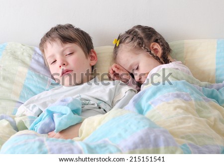Two diseased children with flu lying in the bed.