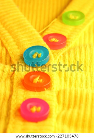 Colorful resin buttons on a yellow shirt.