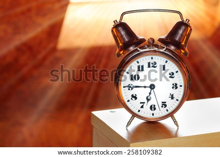 Retro alarm clock in bedroom early morning. First sunrays in your bed, a new day begins.