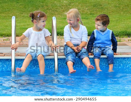 Three little friends have a fun in swimming pool. Happy holidays concept.