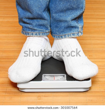 Overweight woman in socks standing on a weighing machine.