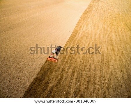 Aerial view of ploughed field with tractor. Industrial background on agricultural theme.