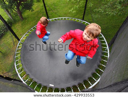 Funny kid playing and jumping on a outdoor trampoline. Children enjoying life. Vacations on countryside. Healthy lifestyle. Multi exposure of only one child playing on garden.