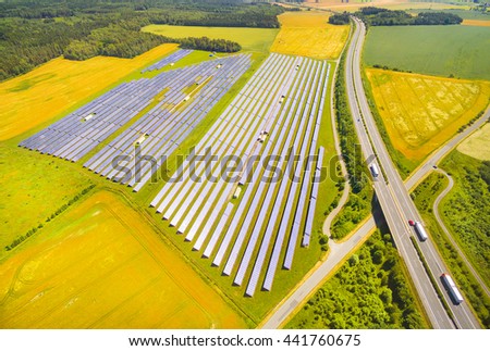 Aerial view to solar power plant near highway with traffic. Industrial background on renewable resources theme.