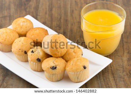 fresh chocolate chip muffins with a glass of orange juice on the table