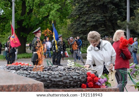 ODESSA,UKRAINE - MAY 9:Old lady put flowers to Eternal Flame in commemoration of Soviet soldiers who fought against Nazi invasion during Second World War in Odessa on May 9,2014 in Odessa,Ukraine