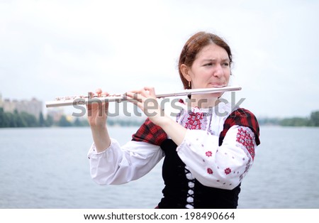 KIEV,UKRAINE - MAY 31:Unidentified beautiful woman on the river playing flute celtic medieval music in traditional scottish clothes during Day of Kiev holiday on May 31,2014 in Kiev,Ukraine