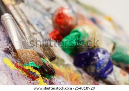 Artistic palette with colourful oil paints, dirty brushes - background for creative art design