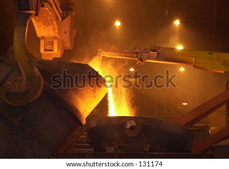 Inside of a steel mill, hot metal pouring.