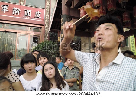 On July 31, 2014 in xi \'an wild goose pagoda scenic area in the square, a folk artists intently rub blowing the calf, lamb, small animals such as rats, to attract tourists.