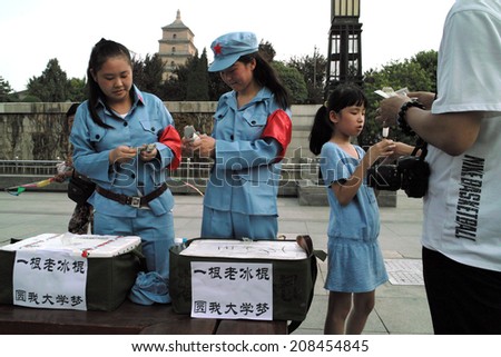 On July 31, 2014, in China, xi 'an wild goose pagoda scenic area, dressed in a red guards, selling old Popsicle work-study programs of the female college students to the tourists.