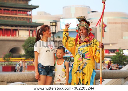 On July 29, 2015, xi 'an, in the clock tower scenic area, a wore a crown, dragon robe, a old man play the part of the emperor, in sorching burning sun, free and tourists.