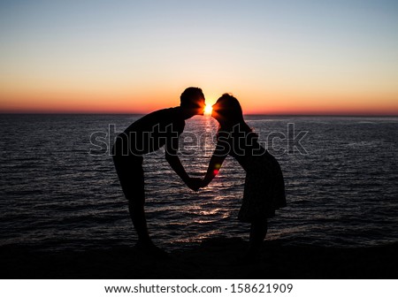 Young couple kissing at the beach with the sun