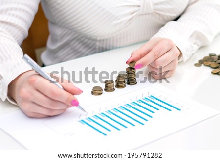 Woman stacks coins. Counting every penny. Depth of field on coins.