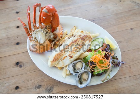 fish steak with big crab and fresh oyster on white plate